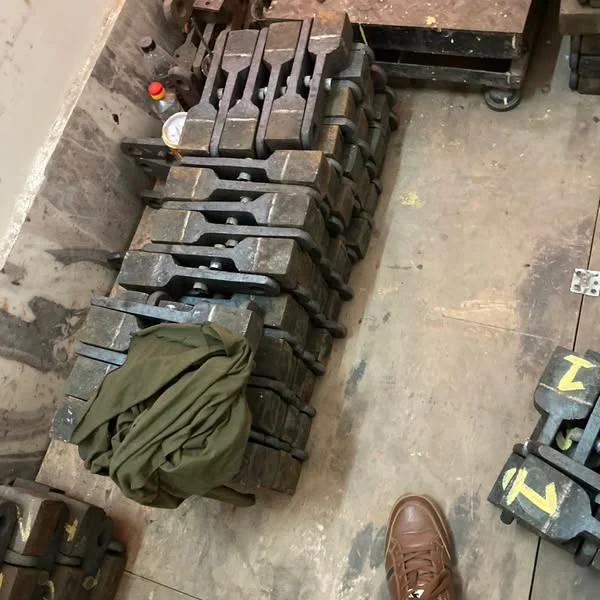 A batch of forged metal hammer components laid out on the workshop floor.