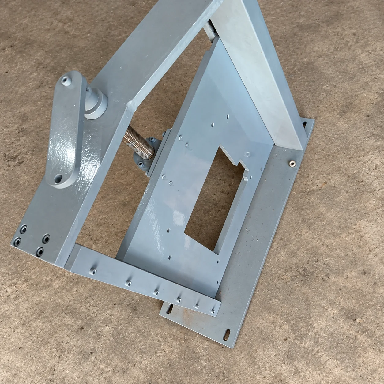 A grey metal guide stand with a rectangular opening and machined mounting holes.