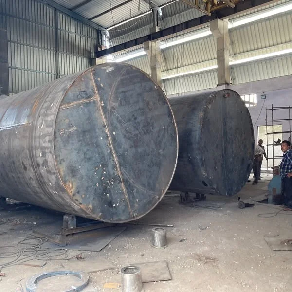 Large cylindrical mild steel tanks under fabrication inside the workshop.